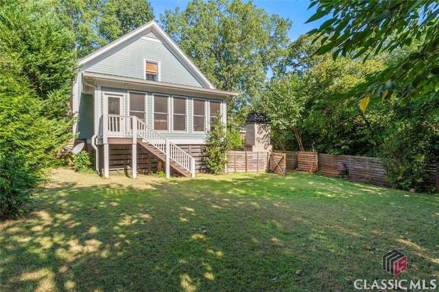 back of house with a sunroom and a yard