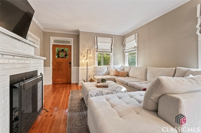 living room featuring a brick fireplace, crown molding, and wood-type flooring