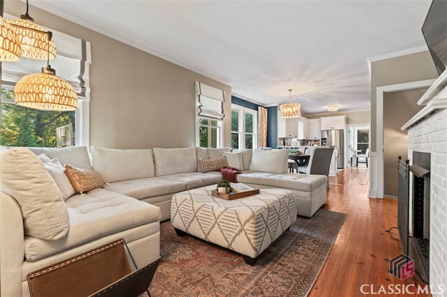 living room with ornamental molding, a brick fireplace, and dark hardwood / wood-style flooring