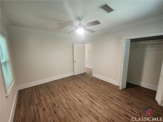 unfurnished bedroom featuring crown molding, dark hardwood / wood-style floors, ceiling fan, and a closet