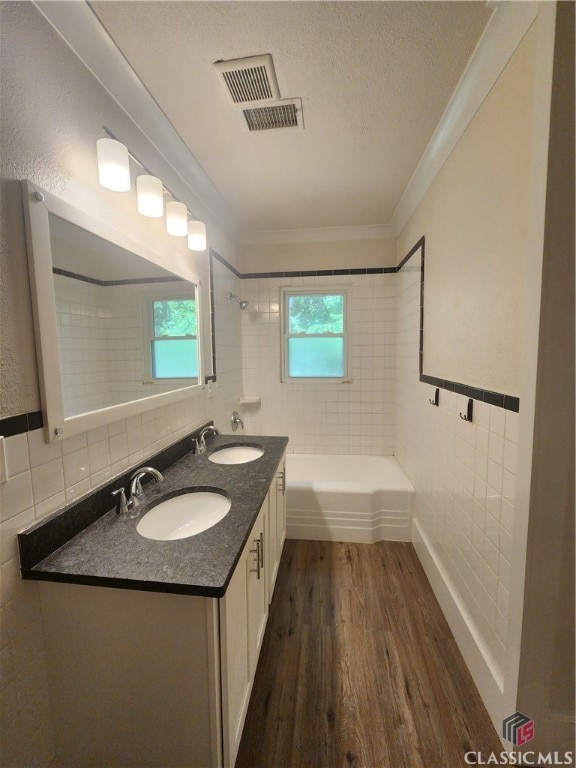 bathroom with tiled shower / bath, vanity, hardwood / wood-style floors, and a healthy amount of sunlight