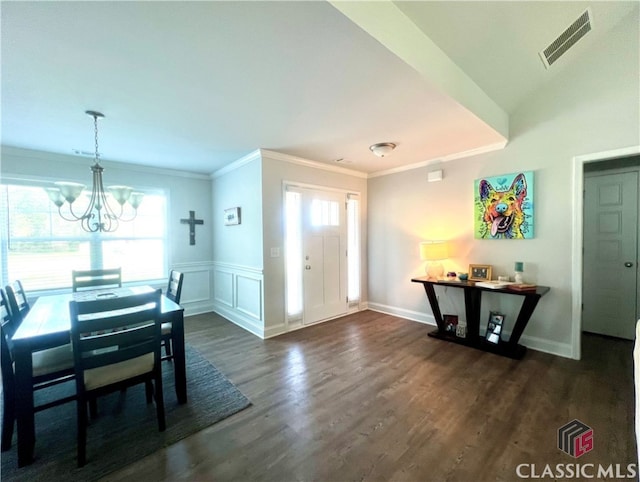 dining area featuring crown molding, dark hardwood / wood-style floors, and a chandelier