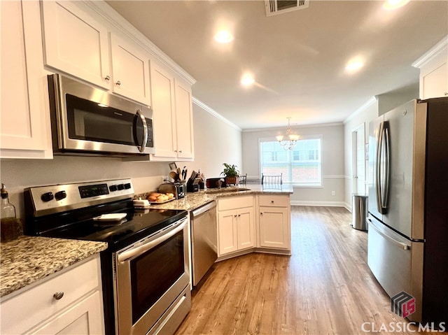 kitchen with white cabinetry, appliances with stainless steel finishes, a notable chandelier, and decorative light fixtures