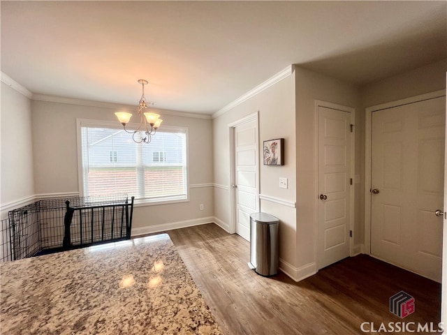 unfurnished dining area featuring hardwood / wood-style floors, ornamental molding, and a chandelier