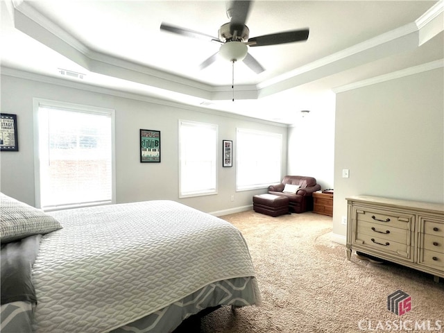 carpeted bedroom with a raised ceiling, ornamental molding, ceiling fan, and multiple windows