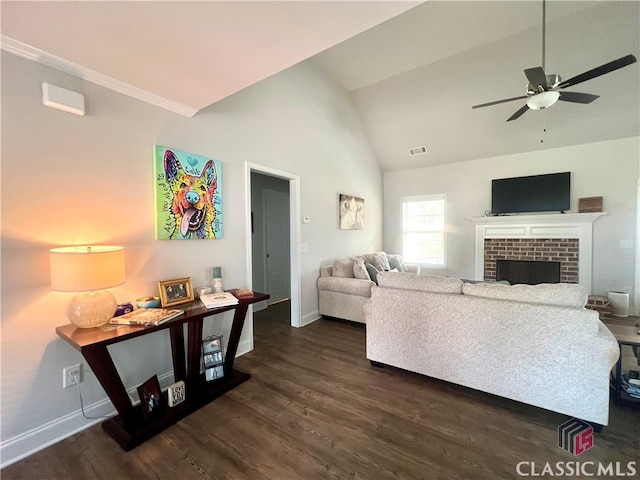 living room with dark wood-type flooring, ceiling fan, a fireplace, and vaulted ceiling