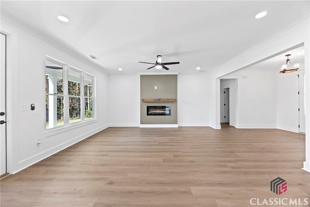 unfurnished living room featuring light hardwood / wood-style flooring, ceiling fan with notable chandelier, and ornamental molding