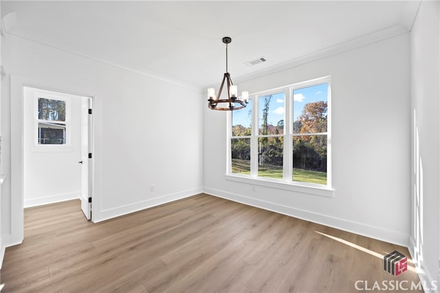 unfurnished dining area with ornamental molding, light hardwood / wood-style floors, and a notable chandelier