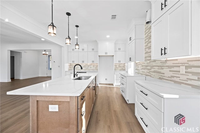 kitchen featuring white cabinetry, sink, a spacious island, and light stone counters