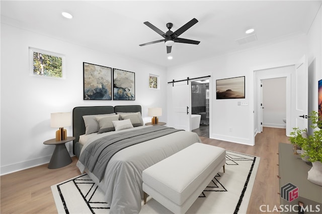 bedroom with crown molding, ceiling fan, a barn door, connected bathroom, and light hardwood / wood-style floors