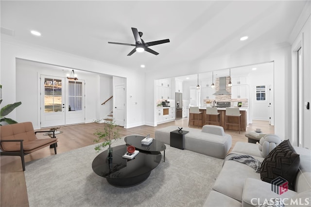 living room featuring ceiling fan, light hardwood / wood-style flooring, and lofted ceiling