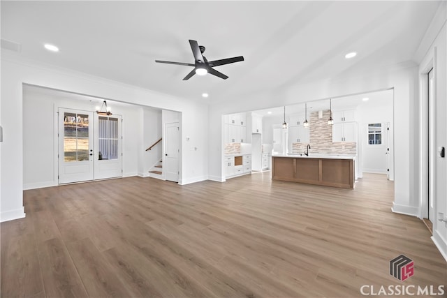 unfurnished living room with ceiling fan, sink, lofted ceiling, and hardwood / wood-style flooring