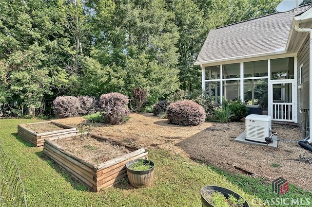 view of yard featuring a vegetable garden and a sunroom