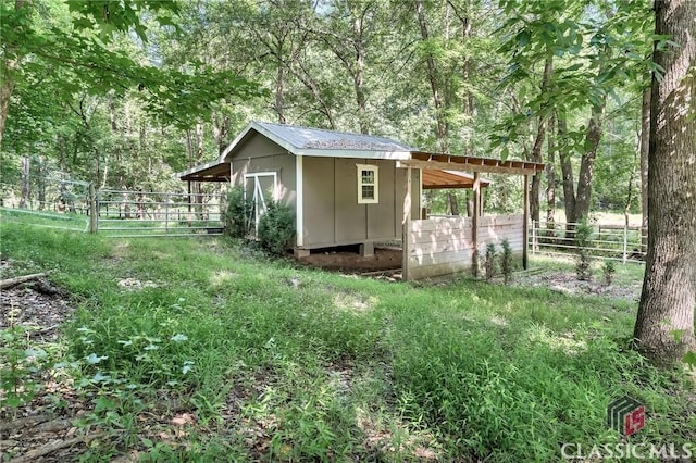 view of shed with fence and a forest view
