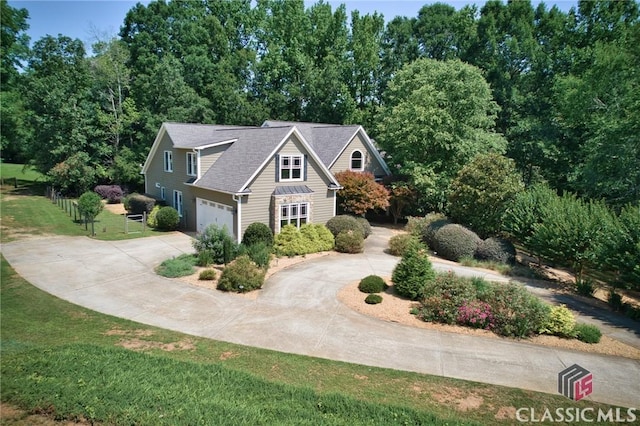 view of front facade with fence, a garage, a front lawn, and curved driveway