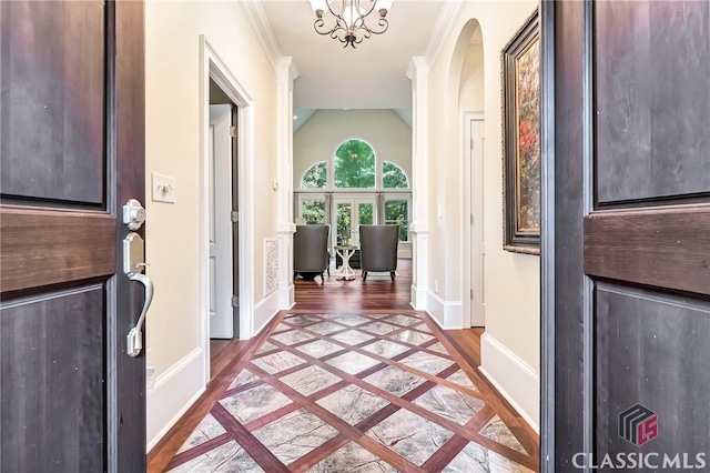 foyer with baseboards, crown molding, light wood-style flooring, and vaulted ceiling