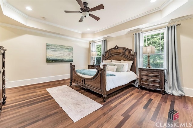 bedroom with a raised ceiling, a ceiling fan, baseboards, ornamental molding, and wood finished floors
