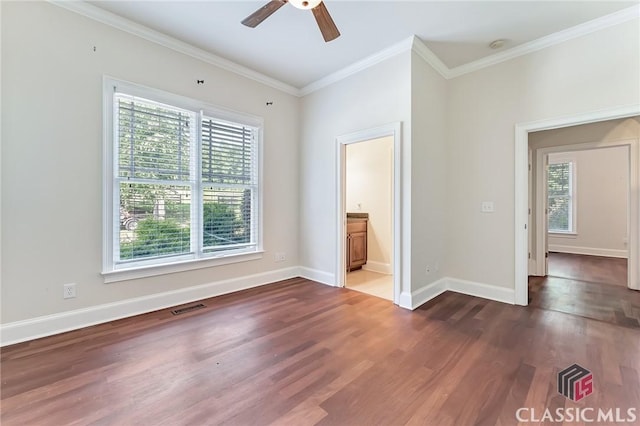 unfurnished bedroom with crown molding, multiple windows, wood finished floors, and visible vents