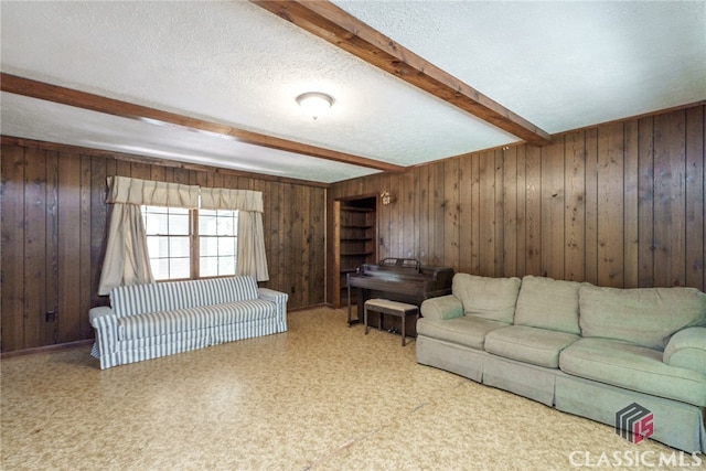 living room with beamed ceiling, wood walls, and a textured ceiling