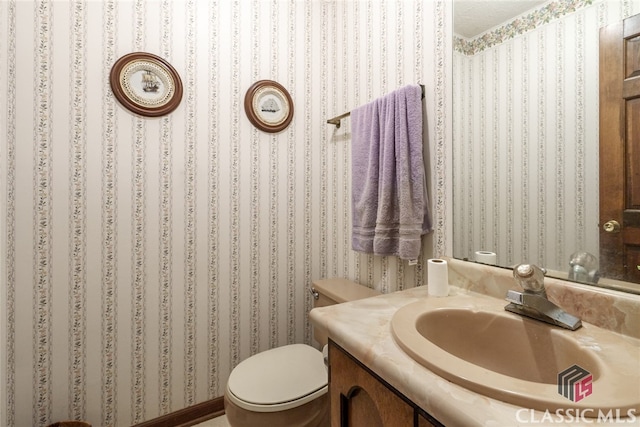 bathroom with a textured ceiling, vanity, and toilet