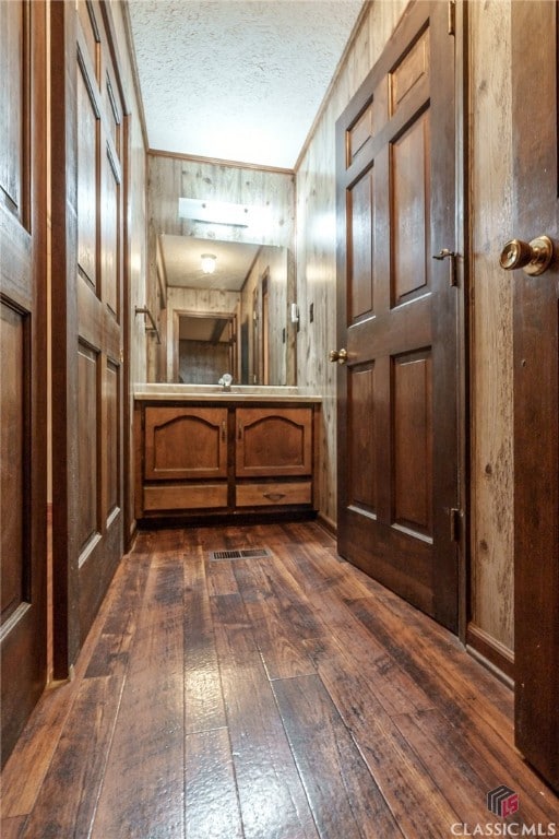 bathroom featuring hardwood / wood-style floors, wooden walls, and a textured ceiling