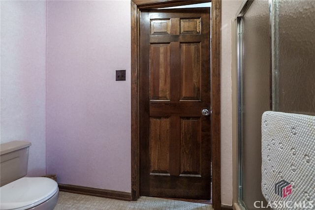 bathroom with tile patterned flooring, toilet, and a shower with door