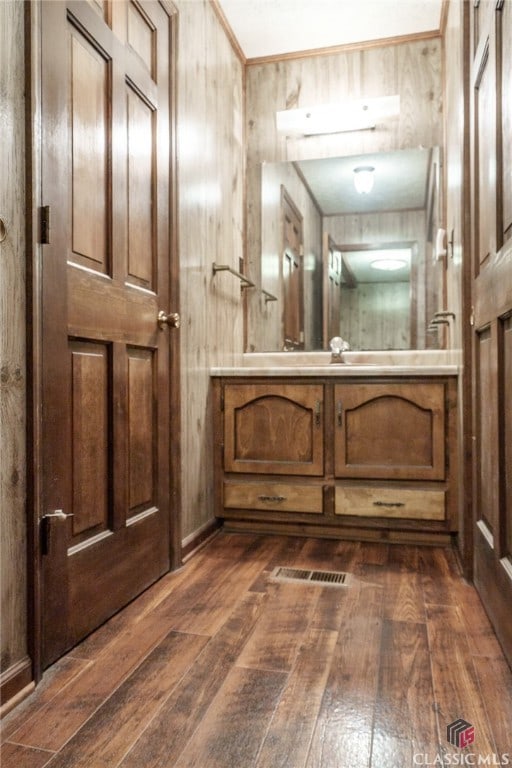 bathroom featuring hardwood / wood-style flooring, wood walls, and vanity