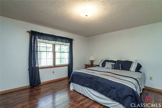 bedroom featuring a textured ceiling and dark hardwood / wood-style flooring