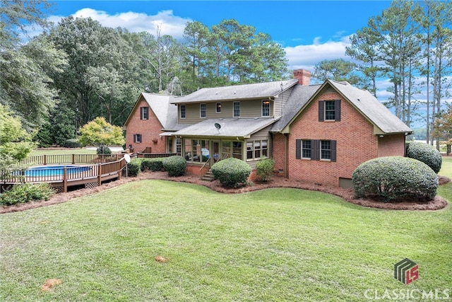 rear view of property with a lawn and a swimming pool side deck