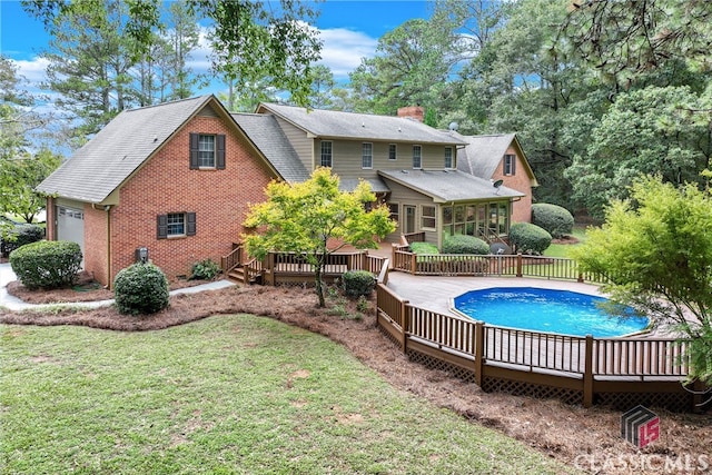 rear view of property with a pool side deck and a lawn