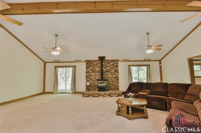 carpeted living room with beamed ceiling, crown molding, a wood stove, and high vaulted ceiling