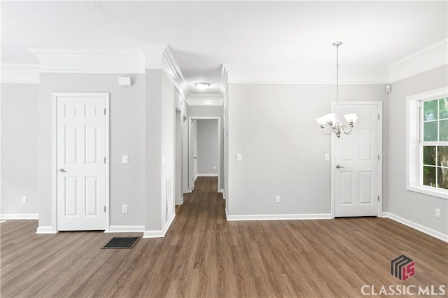 spare room with dark hardwood / wood-style flooring, a notable chandelier, and ornamental molding