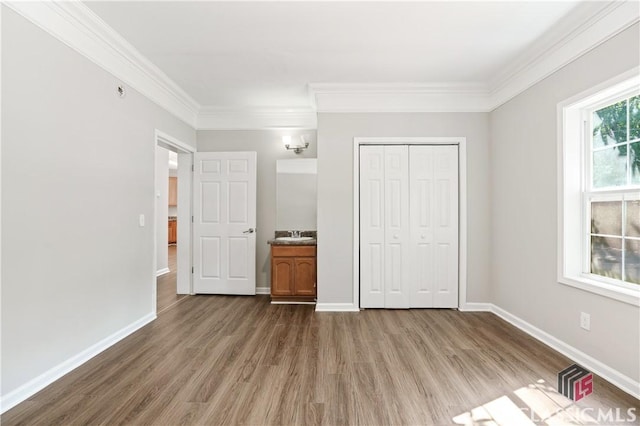 unfurnished bedroom with crown molding, hardwood / wood-style flooring, and a closet