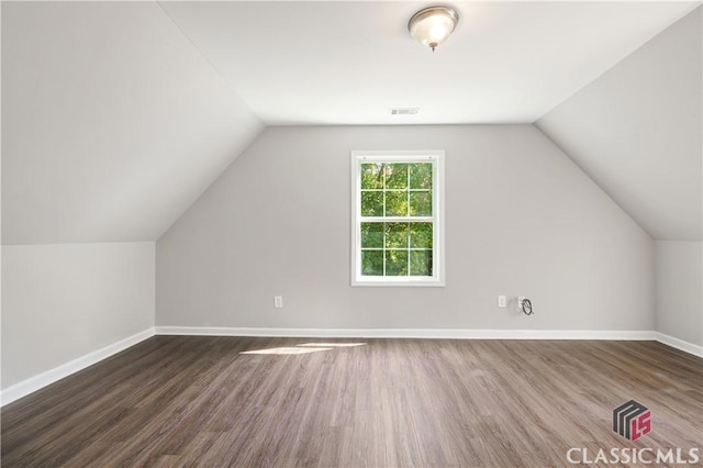 additional living space featuring vaulted ceiling and dark wood-type flooring