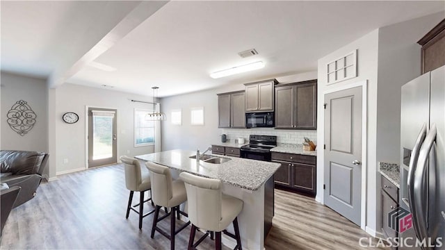 kitchen featuring black appliances, decorative backsplash, open floor plan, and light wood-style floors