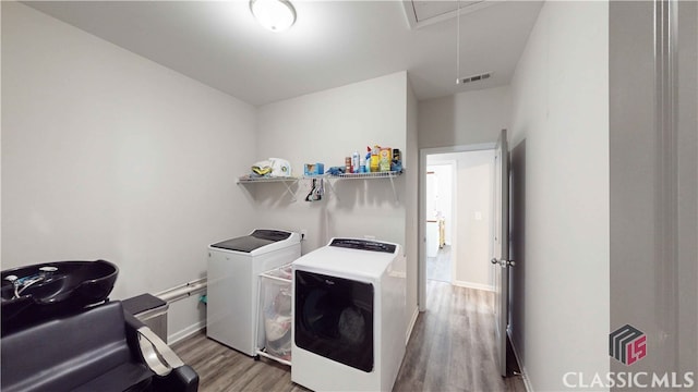 laundry area with independent washer and dryer and hardwood / wood-style flooring