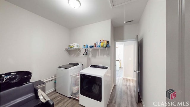 washroom with attic access, visible vents, separate washer and dryer, wood finished floors, and laundry area