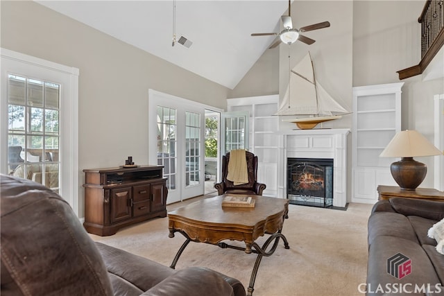 carpeted living room featuring a wealth of natural light, a large fireplace, high vaulted ceiling, and ceiling fan