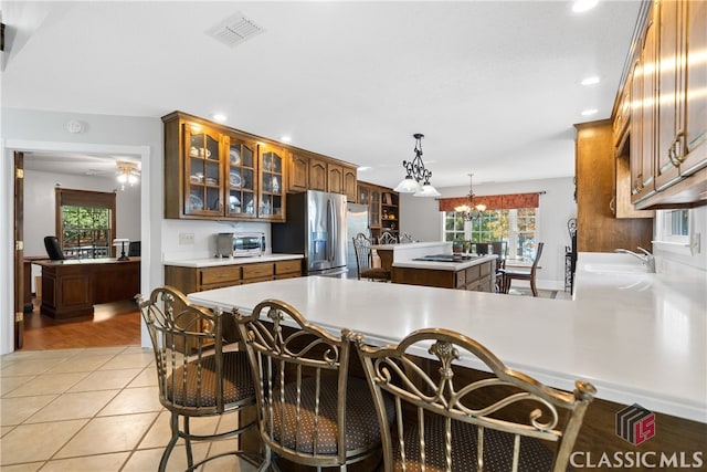 kitchen with sink, a center island, hanging light fixtures, stainless steel fridge with ice dispenser, and light tile patterned floors