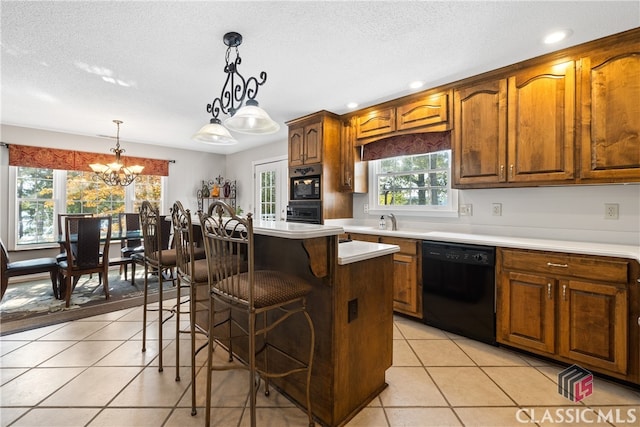 kitchen featuring a kitchen island, a breakfast bar area, black appliances, decorative light fixtures, and a chandelier