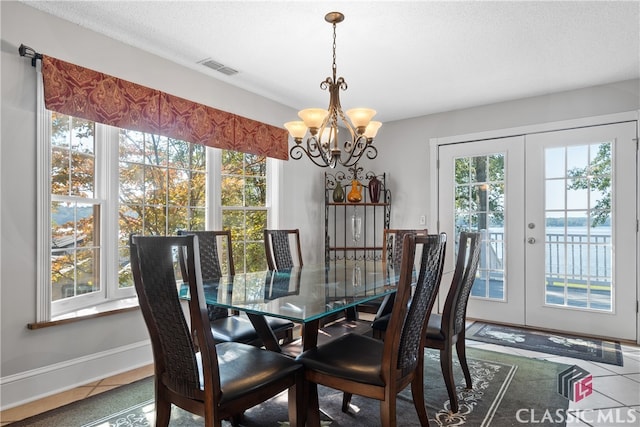 dining room featuring french doors, a water view, a chandelier, and tile patterned flooring