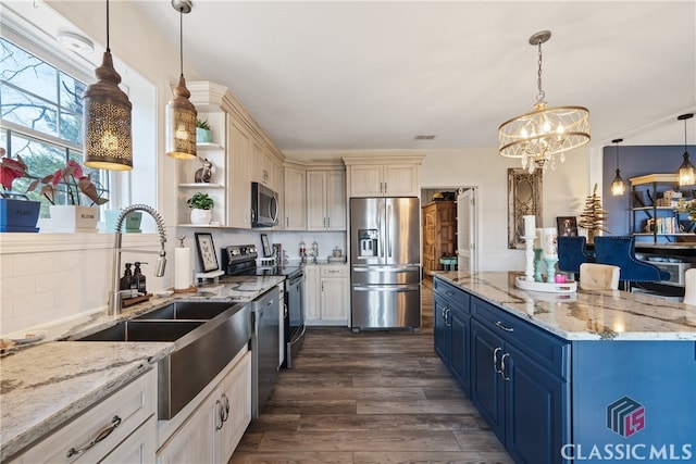 kitchen featuring appliances with stainless steel finishes, sink, pendant lighting, dark wood-type flooring, and blue cabinetry