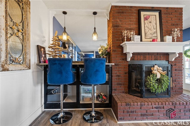 bar with pendant lighting, crown molding, and wood-type flooring