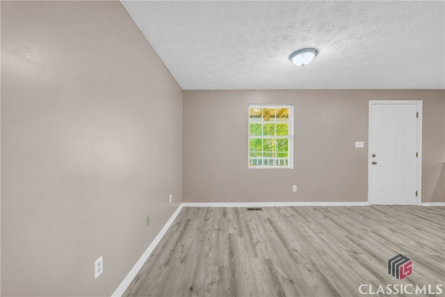 unfurnished room featuring light hardwood / wood-style flooring and a textured ceiling