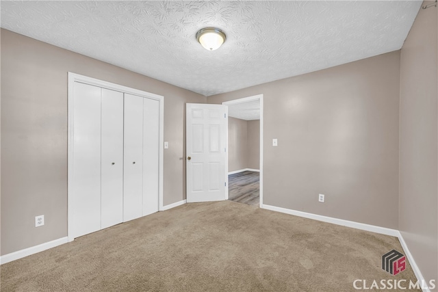 unfurnished bedroom with carpet, a textured ceiling, and a closet