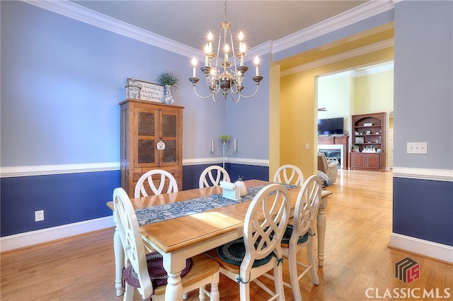 dining space with an inviting chandelier, light hardwood / wood-style flooring, and ornamental molding