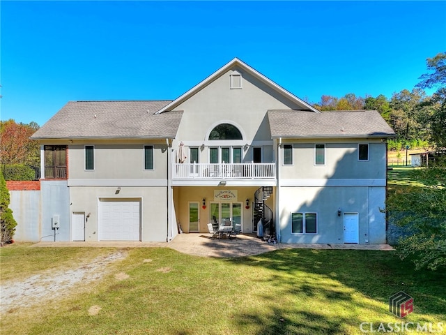 rear view of property with a patio area, a lawn, a balcony, and a garage