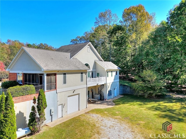 back of property with a balcony, a garage, and a lawn