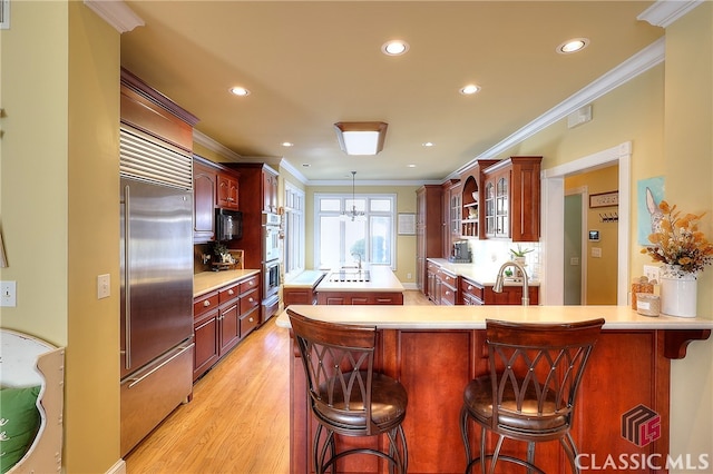 kitchen featuring light hardwood / wood-style floors, appliances with stainless steel finishes, kitchen peninsula, and a kitchen breakfast bar