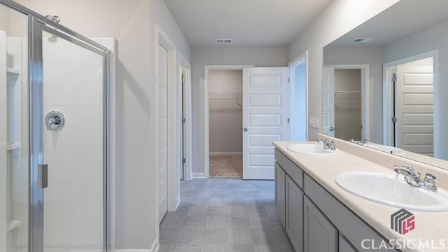 bathroom featuring a shower with door and vanity